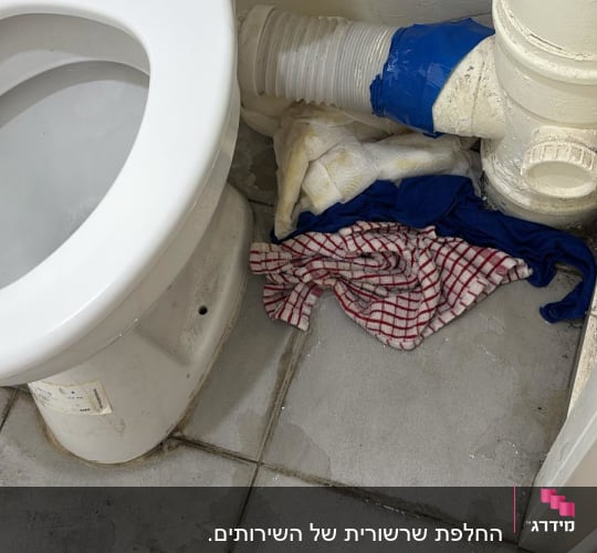 אסלה עם צינור דולף ומטליות על הרצפה